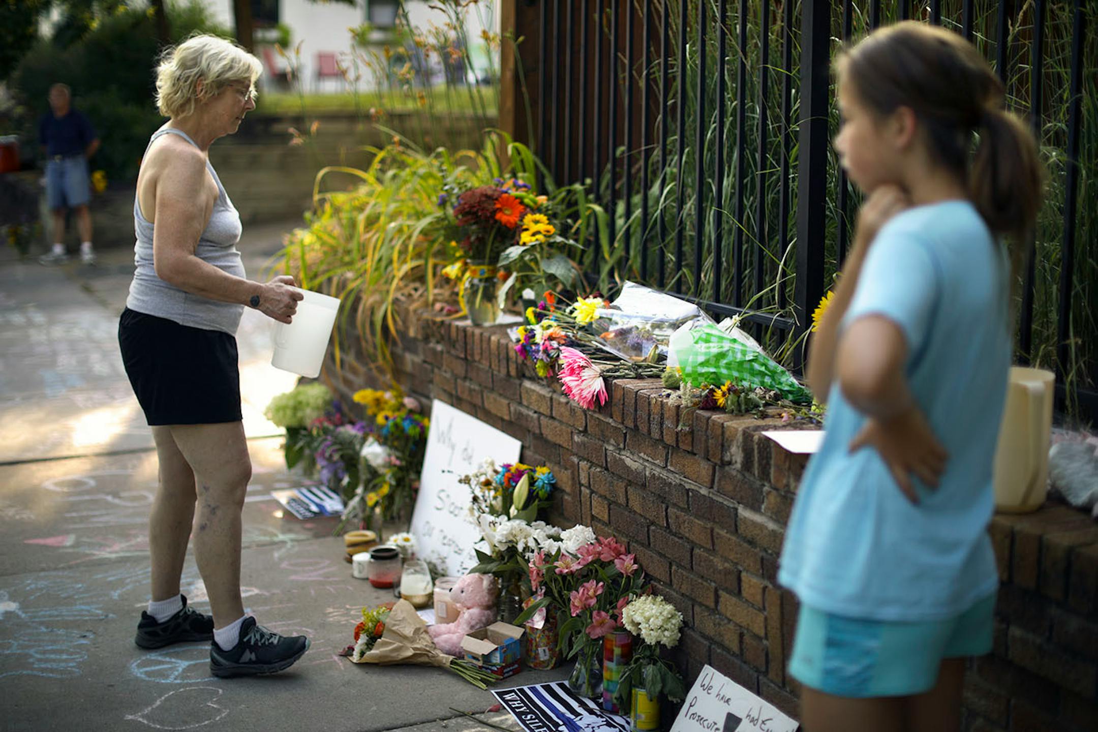 A neighbor added water to flower arrangements left on the sidewalk near the alley on W. 51st St. in the Fulton neighborhood Monday night.