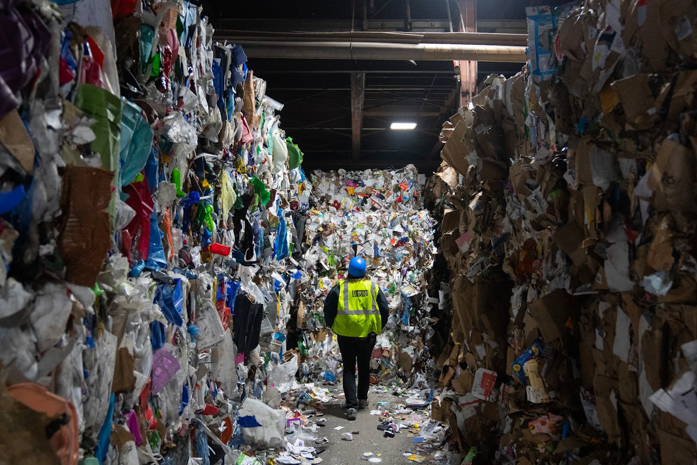 Miriam Holsinger, co-president of Eureka Recycling, walks between bales of recycled materials to examine bales of trash that was sorted out Tuesday, Jan. 09, 2024, at Eureka Recycling in Minneapolis, Minn. ]