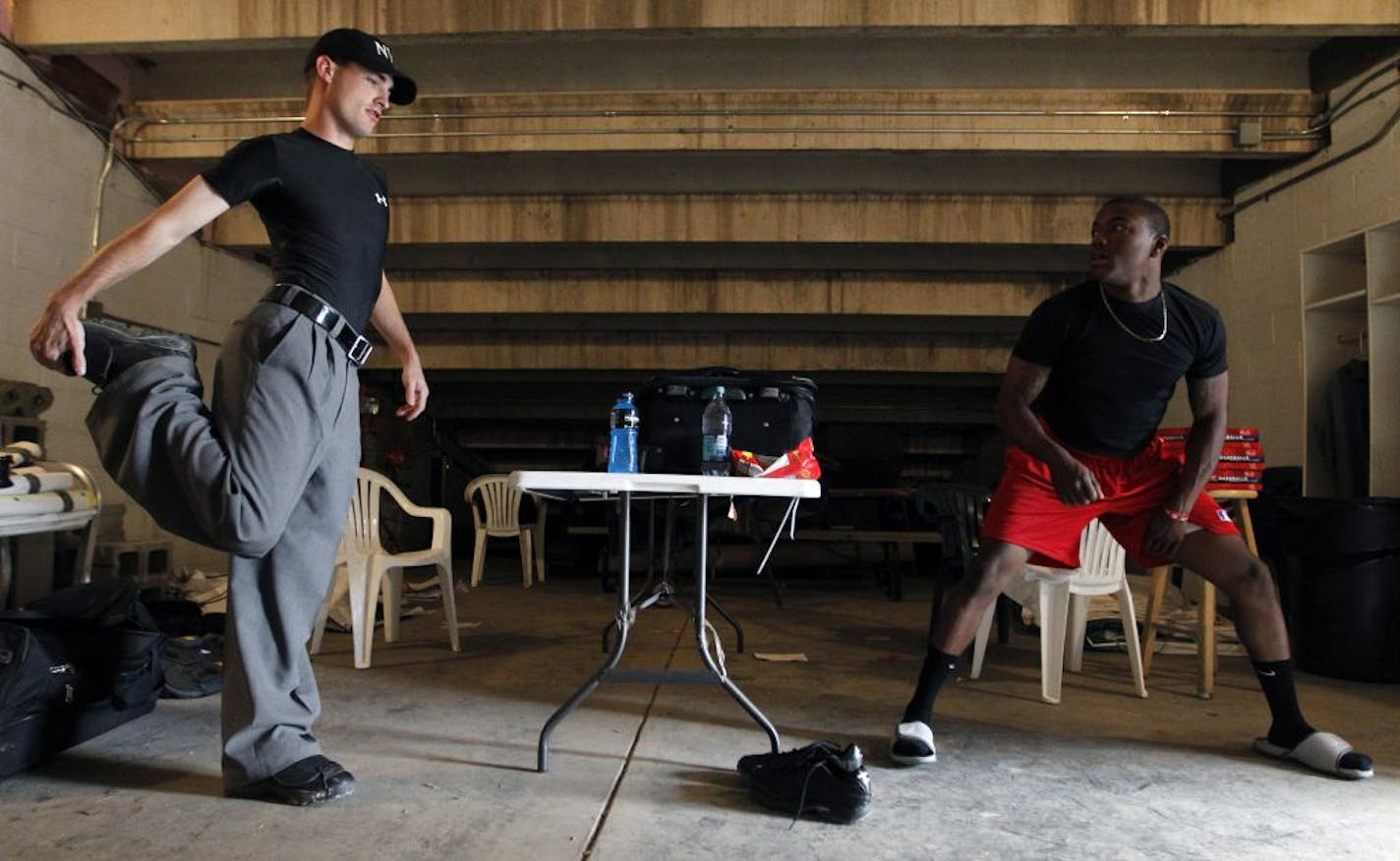 At Franklin Rogers Park, Sam Hansen and Malachi Moore stretch out before a game between the Mankato Moondogs and the Brainerd Lunkers. Both have played competitive baseball and understand that umpires have to be limber and quick to do their job and avoid injury.