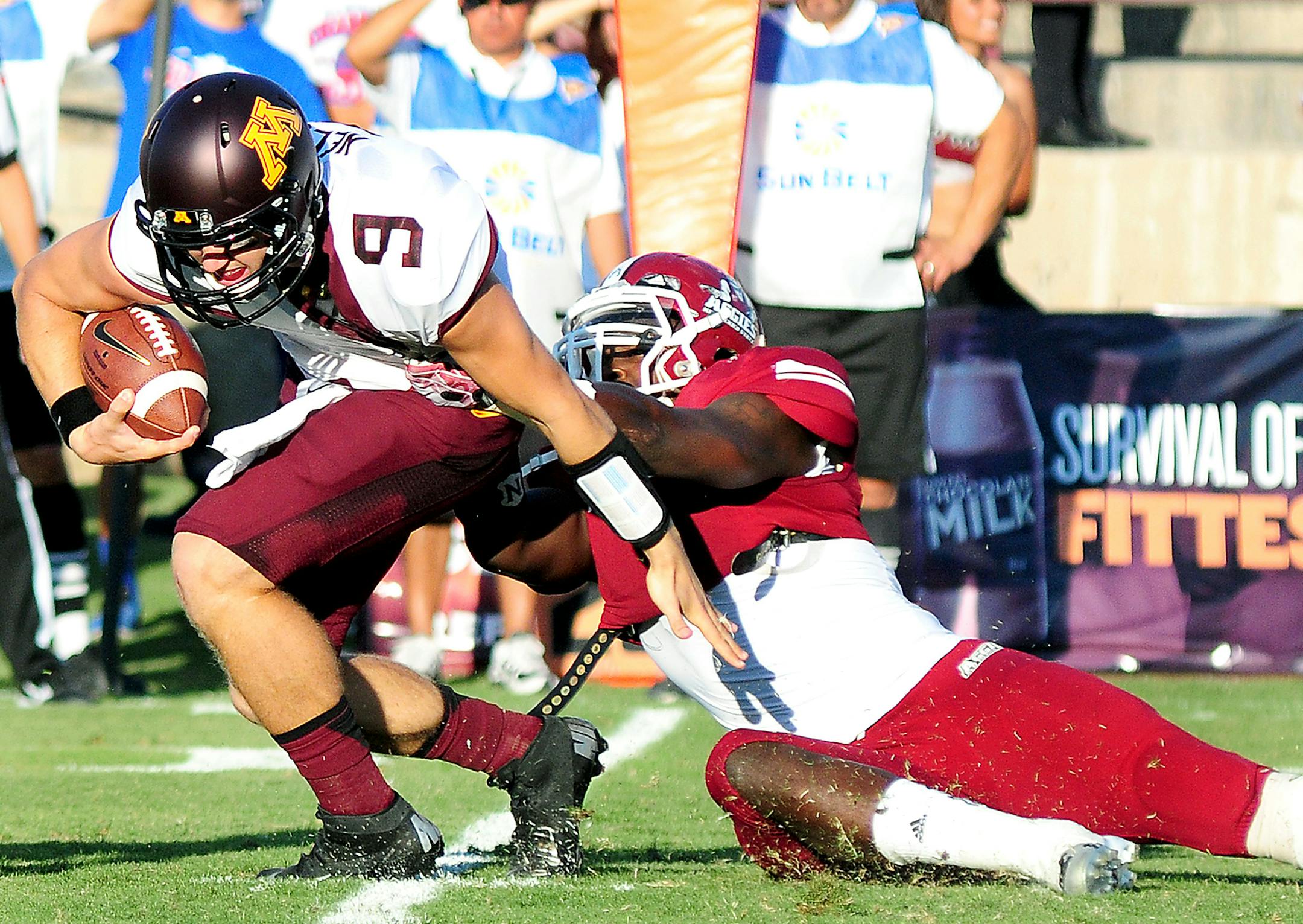 Photos by Shari Vialpando-Hill Minnesota University quarterback Philip Nelson runs a keeper as New Mexico State linebacker Trashaun Nixon attempts to break his stride during the first half of the game at Aggie Memorial Stadium in Las Cruces, N.M.