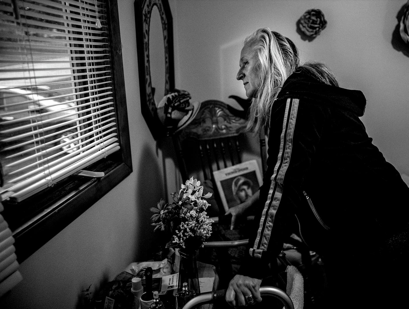 Patricia Wilson looks out of the bedroom at her group home to see if her mother has arrived. Her mother, Janet Resler, takes Wilson out to community meals most nights because they find the food to be unpalatable at the group home.