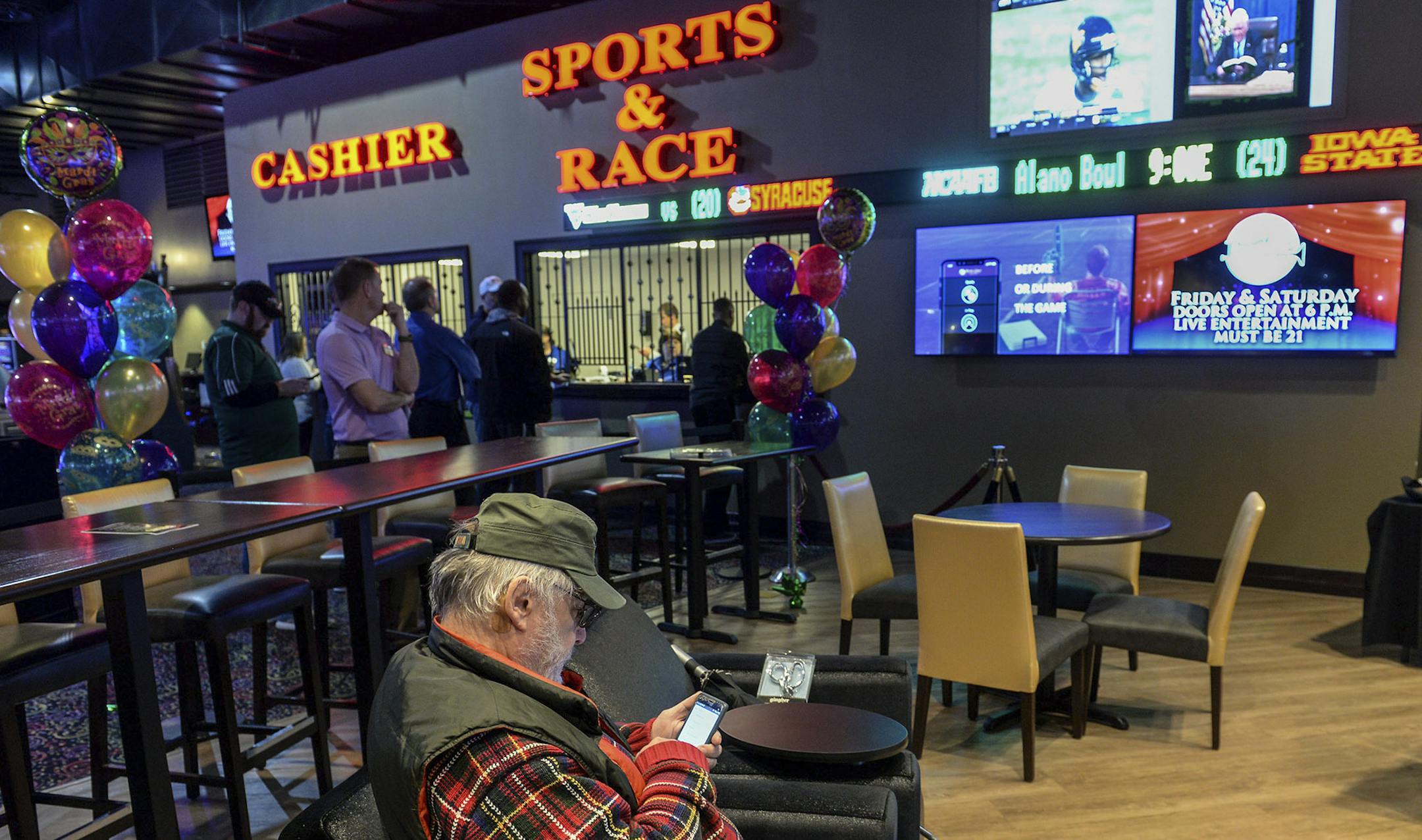 Tom Baldwin of Paint Creek, W.V., tries to download the new online sports betting application onto his smart phone soon after the official ribbon cutting opening of the sportsbook betting app at Mardi Gras Casino & Resort in Crosslanes, W.V. Friday Dec. 28, 2018. (Chris Dorst/Charleston Gazette-Mail via AP)