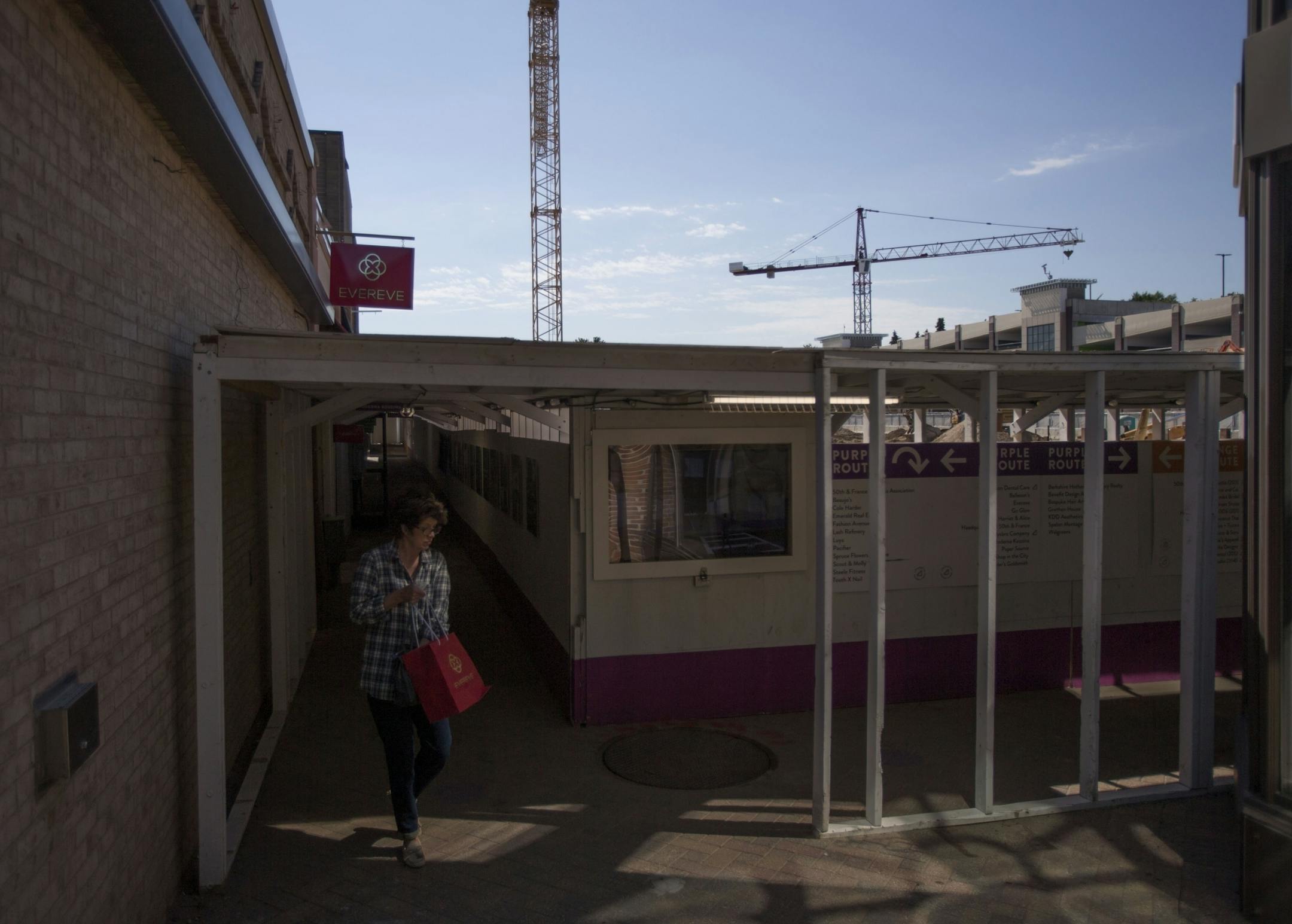 A shopper attempts to navigate the boardwalk separating the shops from the construction site.