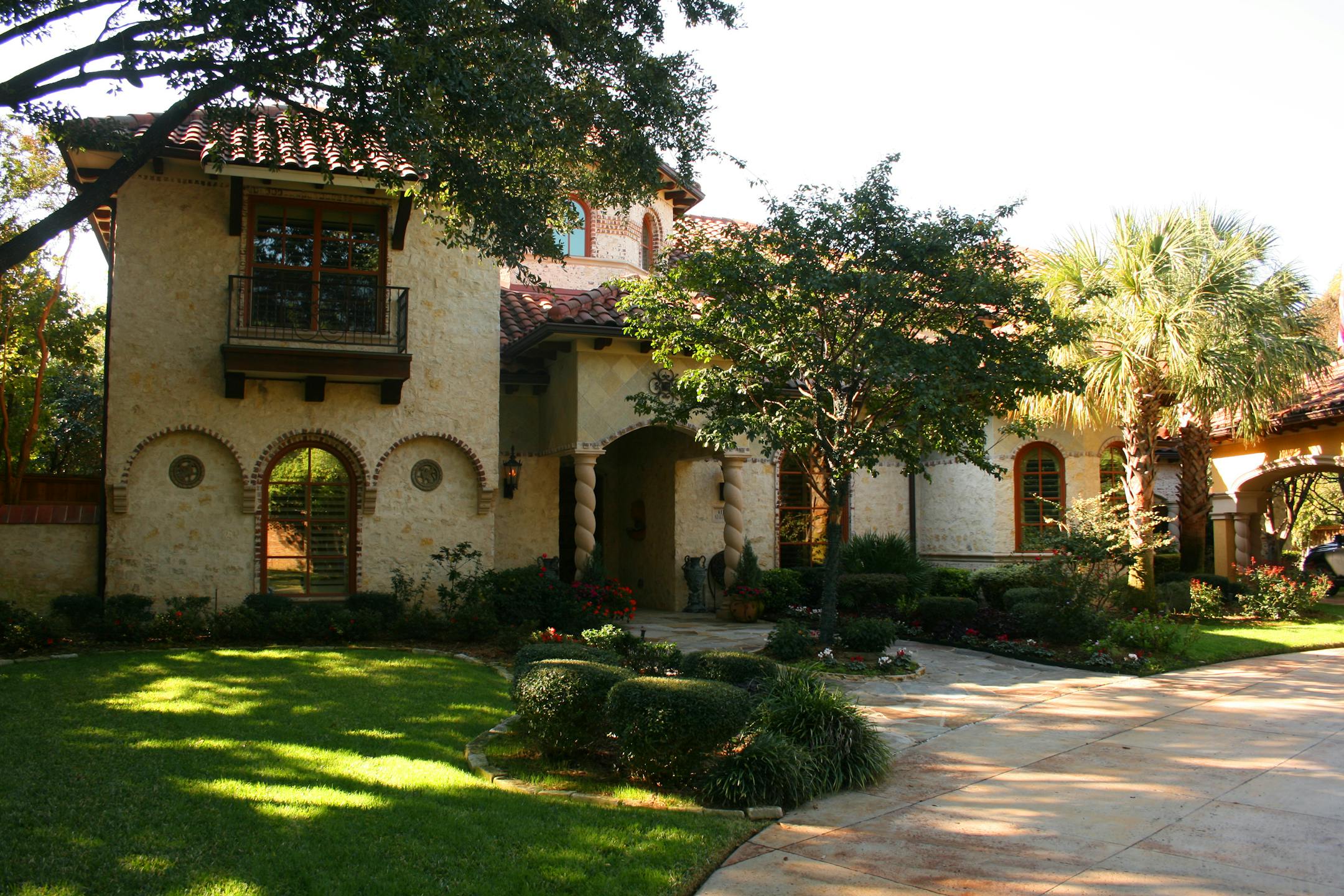 Spanish style house with a tile roof, curved driveway, arch window details.