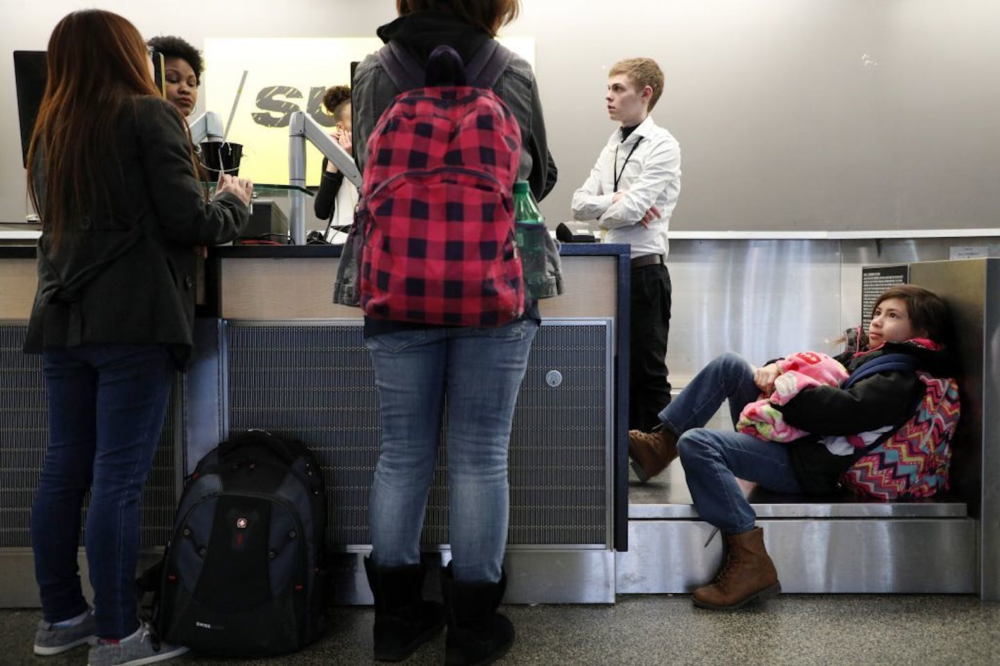 Percy Huston, 11, sat on a luggage scale as she waited for her mom and aunt to rebook their flights to Las Vegas for a wedding after MSP grounded flights Saturday due to the snow.