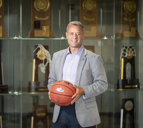 Athletic Director Phil Esten stood for a photo in front of the trophy case at the University of St. Thomas