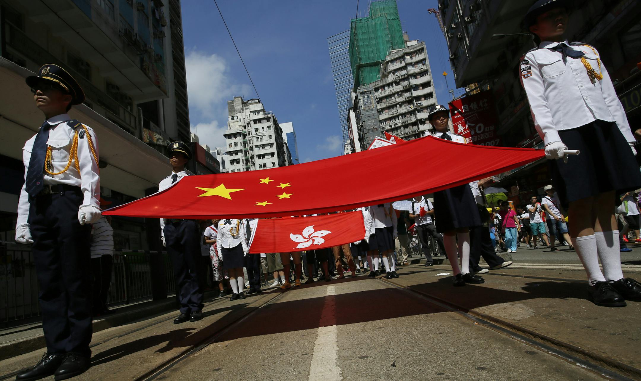 Participants hold a Chinese national flag and a Hong Kong flag as tens of thousands of people march on a down town street to oppose a planned civil disobedience campaign by pro-democracy activists in Hong Kong, Sunday, Aug. 17, 2014. The rally was organized by a pro-Beijing group. Many carried banners or shouted slogans saying they were opposed to the Occupy Central pro-democracy movement. (AP Photo/Vincent Yu)