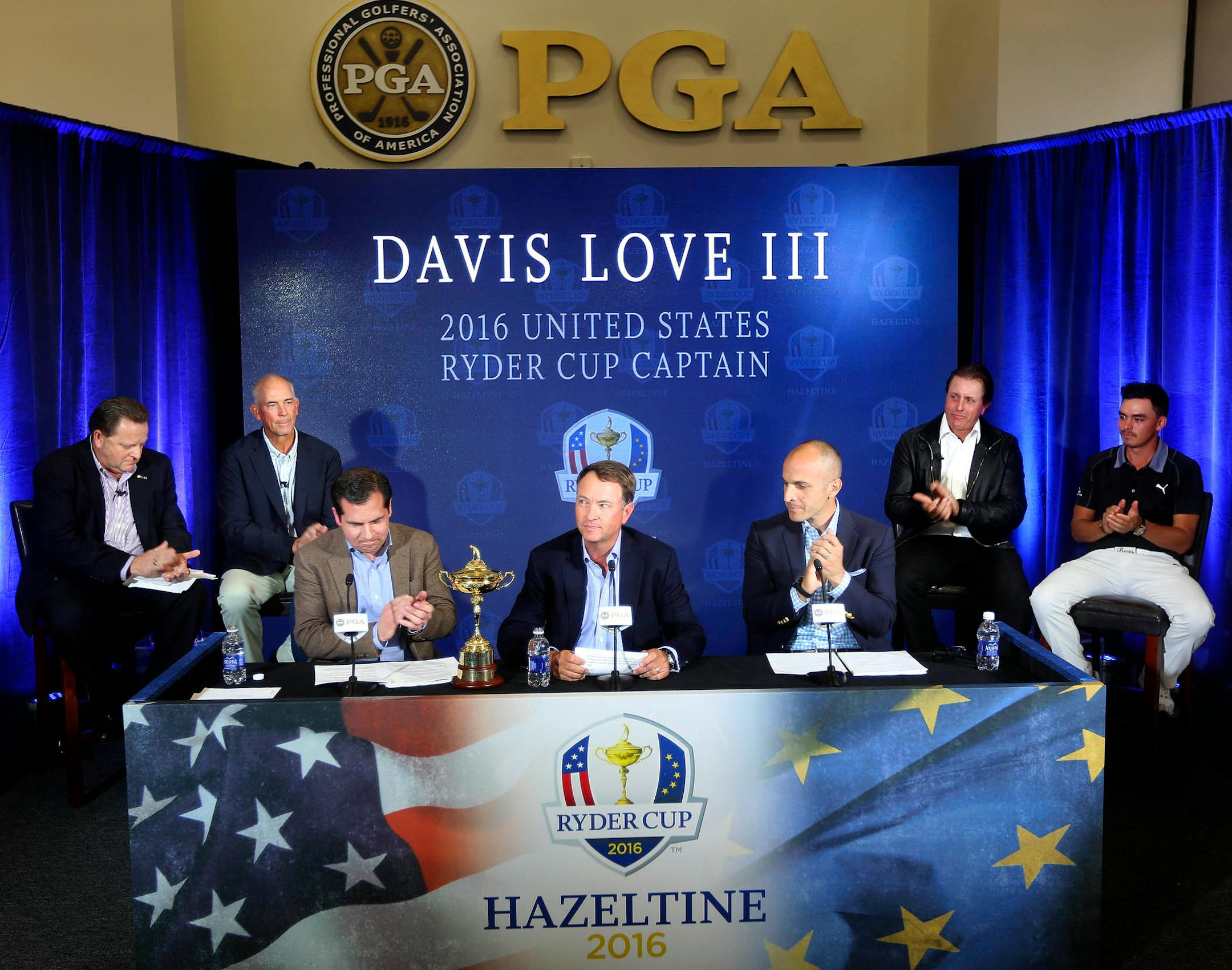 Davis Love III, center, receives applause during a news conference Tuesday, Feb. 24, 2015, at PGA of America headquarters in Palm Beach Gardens, Fla.Love was named captain of the 2016 U.S. Ryder Cup team. From left are Paul Levy, PGA of America vice president; Tom Lehman, vice captain; Derek Sprague, president of the PGA; Love; Peter Bevacqua, CEO of the PGA; Phil Mickelson; and Rickie Fowler.