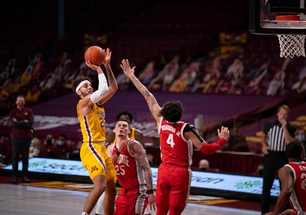 Minnesota Gophers guard Gabe Kalscheur (22) let a first half shot fly over the defense of Ohio State Buckeyes forward Kyle Young (25) and guard Duane 