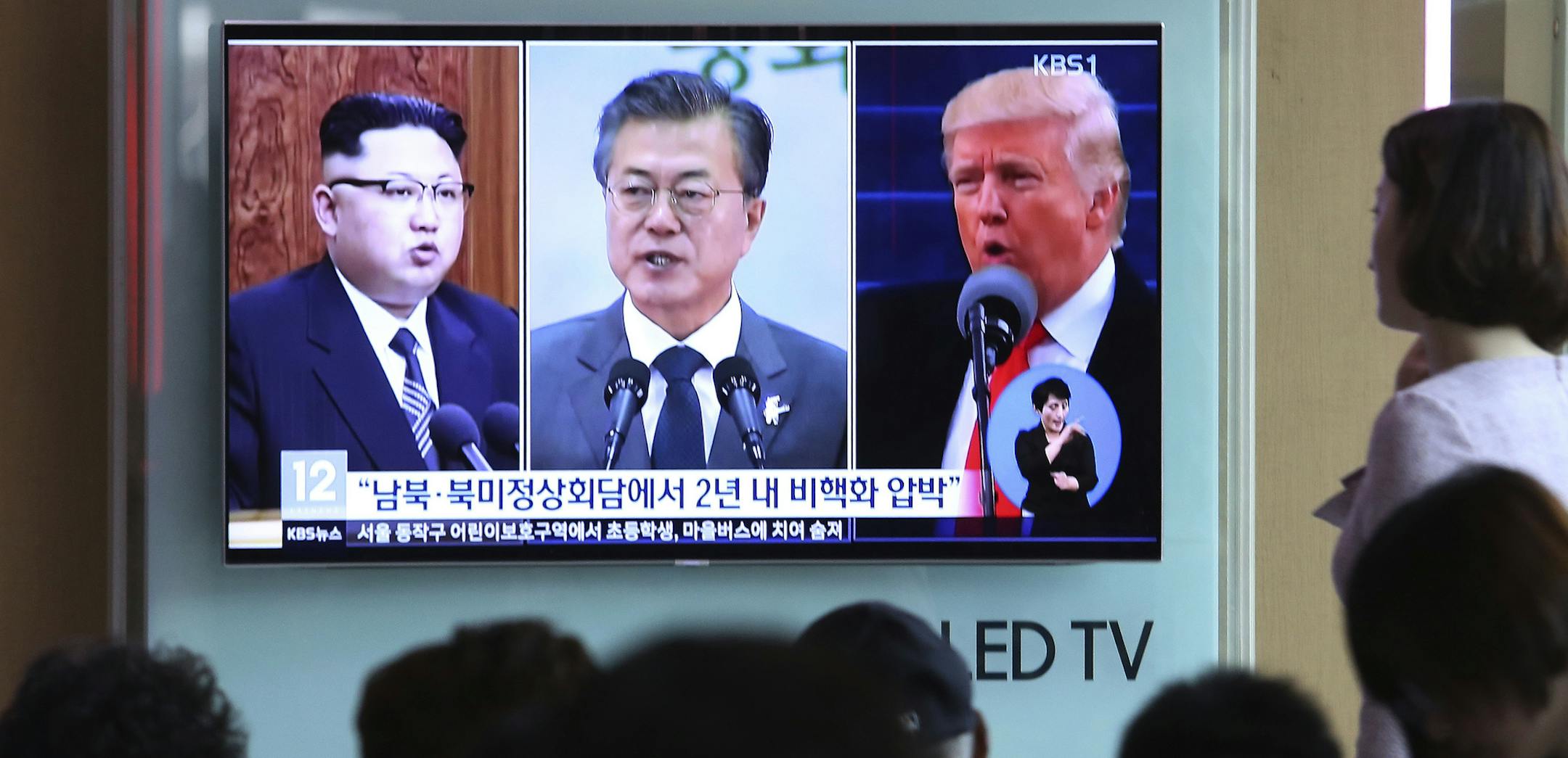 FILE - In this Wednesday, April 18, 2018, file photo, people watch a TV screen showing file footage of U.S. President Donald Trump, right, South Korean President Moon Jae-in and North Korean leader Kim Jong Un, left, during a news program at the Seoul Railway Station in Seoul, South Korea. The upcoming meeting between the leaders of the rival Koreas will be the ultimate test of Moon ís belief that his nation should lead international efforts to deal with North Korea.The signs read: " Summit