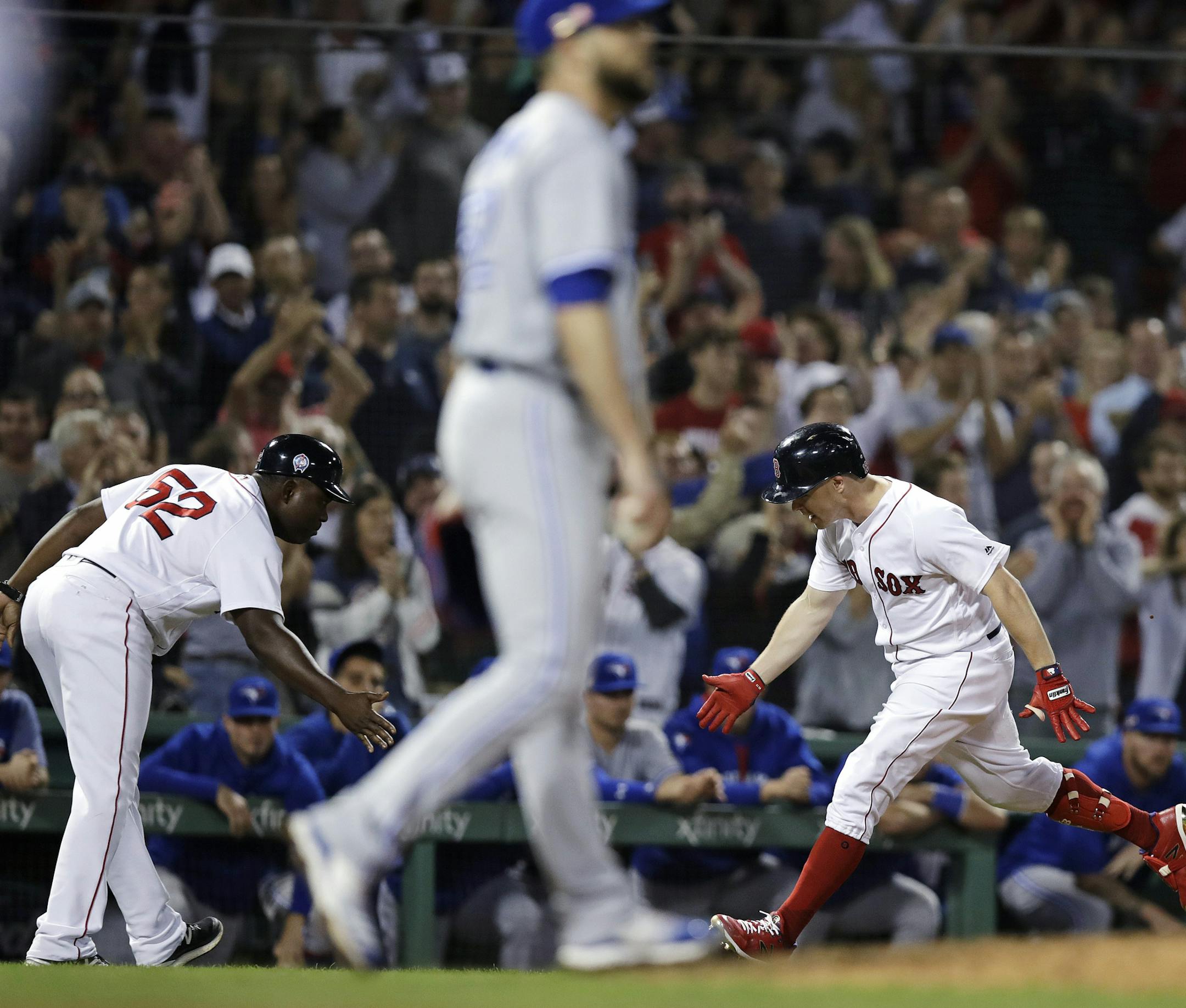 Boston Red Sox's Brock Holt, right, low-fives third base coach Carlos Febles (52) after his pinch-hit, three run home run off Toronto Blue Jays relief pitcher Ryan Tepera, center, during the seventh inning of a baseball game at Fenway Park in Boston, Tuesday, Sept. 11, 2018. (AP Photo/Charles Krupa)