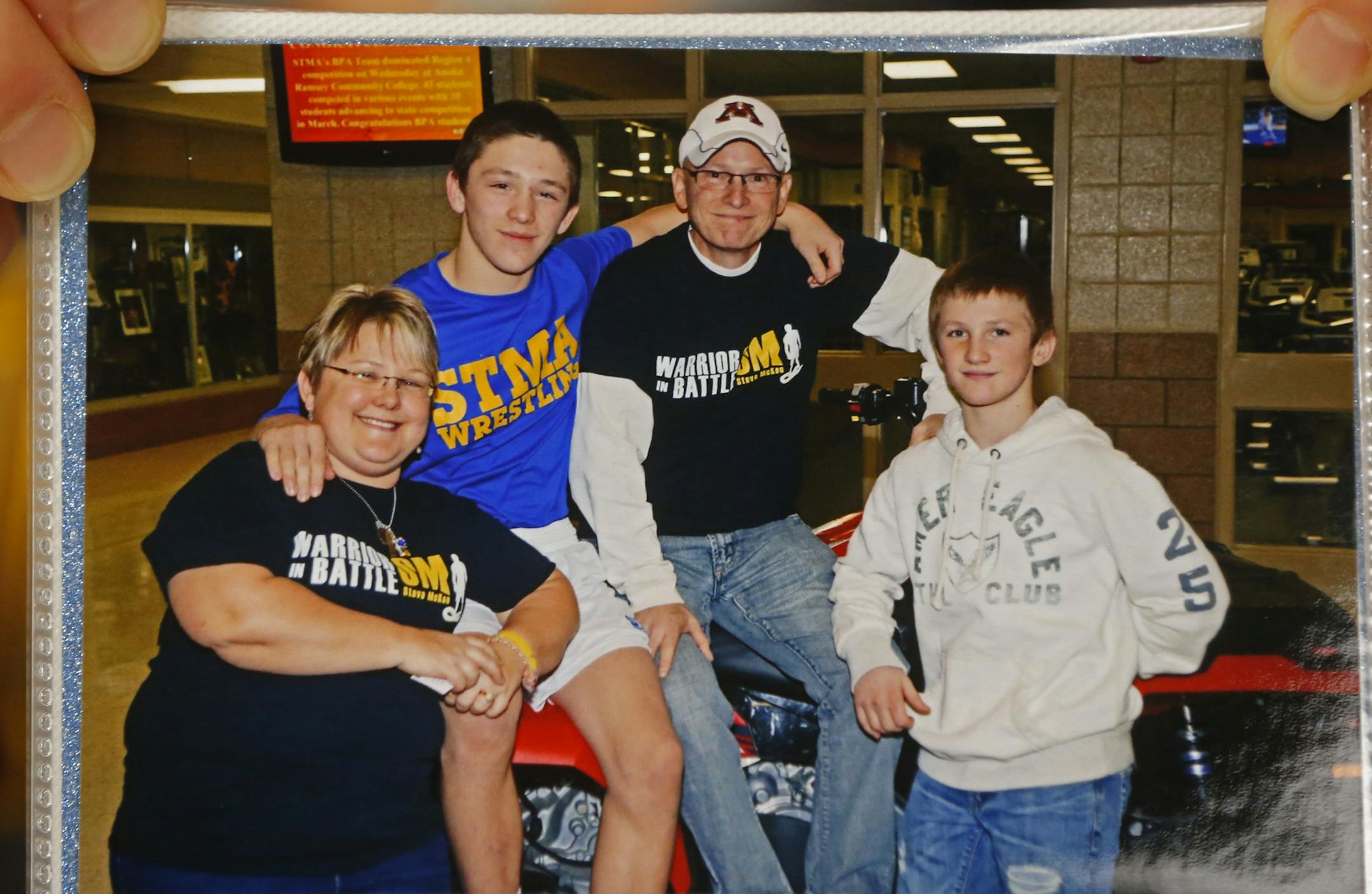 At St. Michael-Albertville H.S., Nina McKee holds a picture of herself with son Mitchell,16, husband, Steve, and son Patrick,14. Mitchell is battling terminal cancer and has been on a chemo drip all week so he can go down to St. Paul and watch his son Mitchell go for a state title in the 120 lbs. class. ]richard tsong-taatarii/rtsong-taatarii@startribune.com