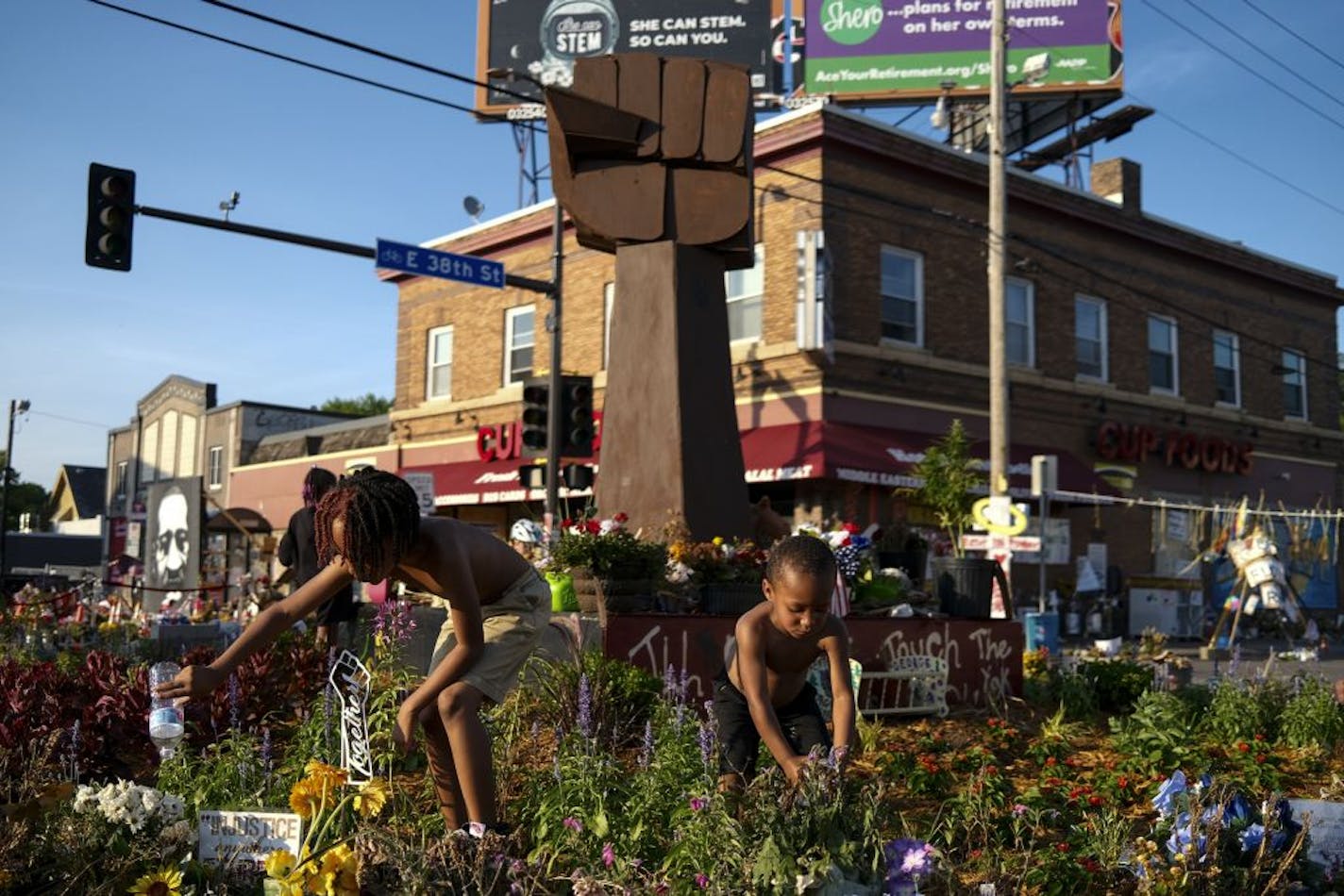 Mister Smith, 7, and his little brother, Sir'Miles Smith, 4, watered the plants at the memorial in the 38th and Chicago intersection near where George Floyd was killed in Minneapolis Police custody in late May.