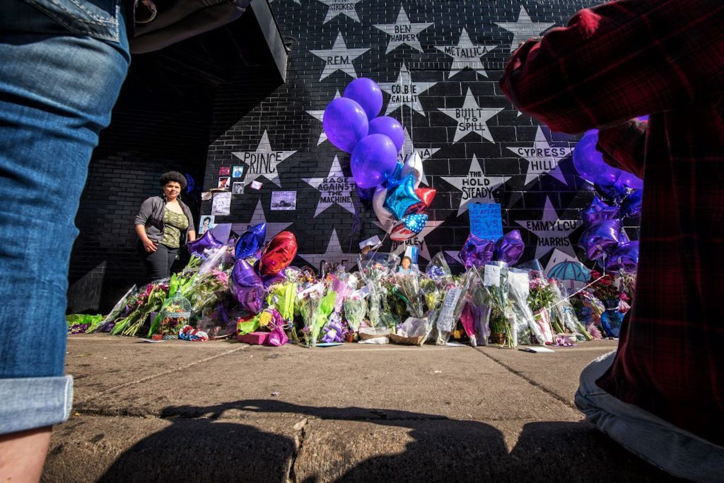 People filed past the makeshift memorial next to Prince's star on First Avenue's wall of stars. They took photos and posed for their own, left letters, purple flowers and balloons. Music by Prince blared from the speakers of passing cars.