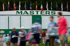 Patrons walk past the main scoreboard during a practice round Tuesday.