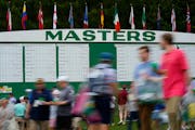 Patrons walk past the main scoreboard during a practice round Tuesday.