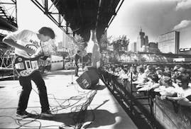 Mike Mills, foreground, of R.E.M. performs at the Rockin' the River open air music festival at Navy Island in St. Paul on May 21, 1983. About 6,000 pe