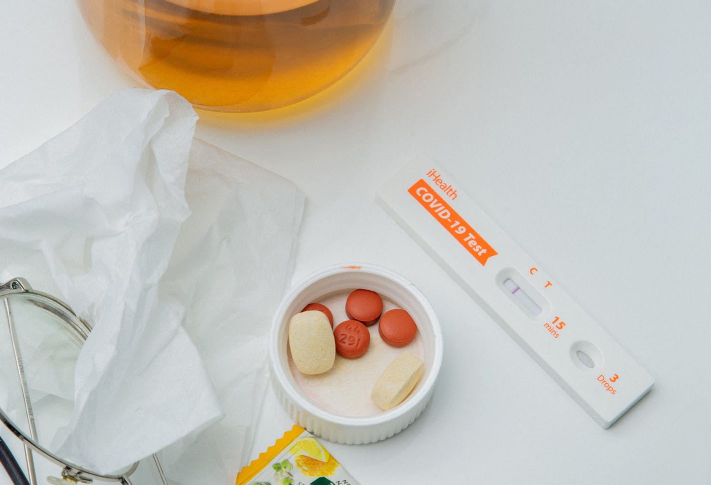 Tea, pills and positive COVID test on white background.