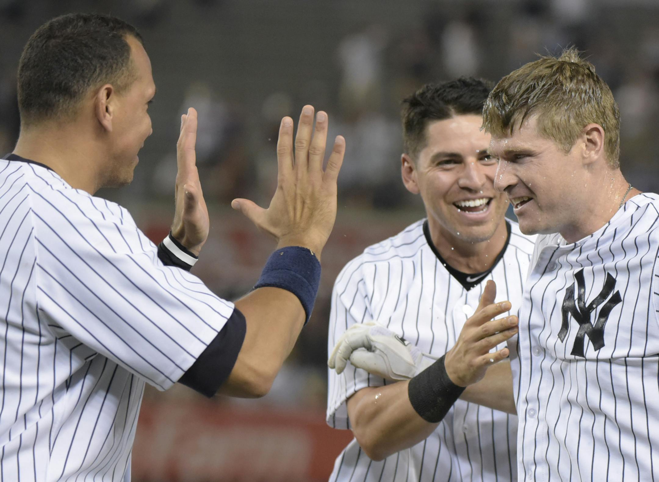 New York Yankees' Chase Headley, right, celebrates with Jacoby Ellsbury and Alex Rodriguez, left, after the winning run scored as Headley grounded out with bases loaded during the 10th inning of a baseball game against the Minnesota Twins Monday, Aug 17, 2015, at Yankee Stadium in New York. The Yankees won 8-7. (AP Photo/Bill Kostroun)