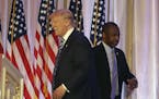 Former Republican presidential candidate Ben Carson, right, walks past Republican presidential candidate Donald Trump, left, after announcing he will 