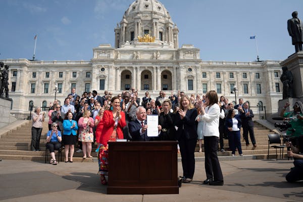 Gov. Tim Walz signs a ceremonial budget bill on the Capitol steps in front of hundreds of supporters on Wednesday, May 24, 2023.