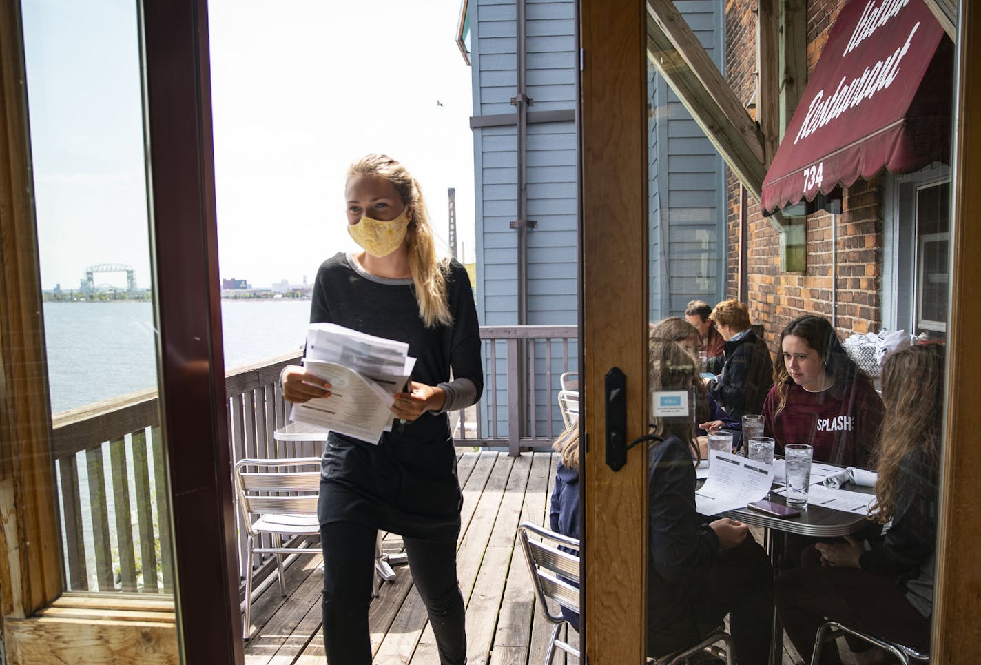 (Left) Abby Claussen, a server at Va Bene Cafe, walked back into the restaurant after taking the lunch order of Duluth diners as they enjoyed the first day of Governor Walz's phased re-opening of the state that began on Monday. ] ALEX KORMANN • alex.kormann@startribune.com The next step in Governor Walz's phased re-opening of the state began on Monday June 1, 2020. Salons and barbershops were allowed to open back up while restaurants were allowed to open outdoor and patio seating.