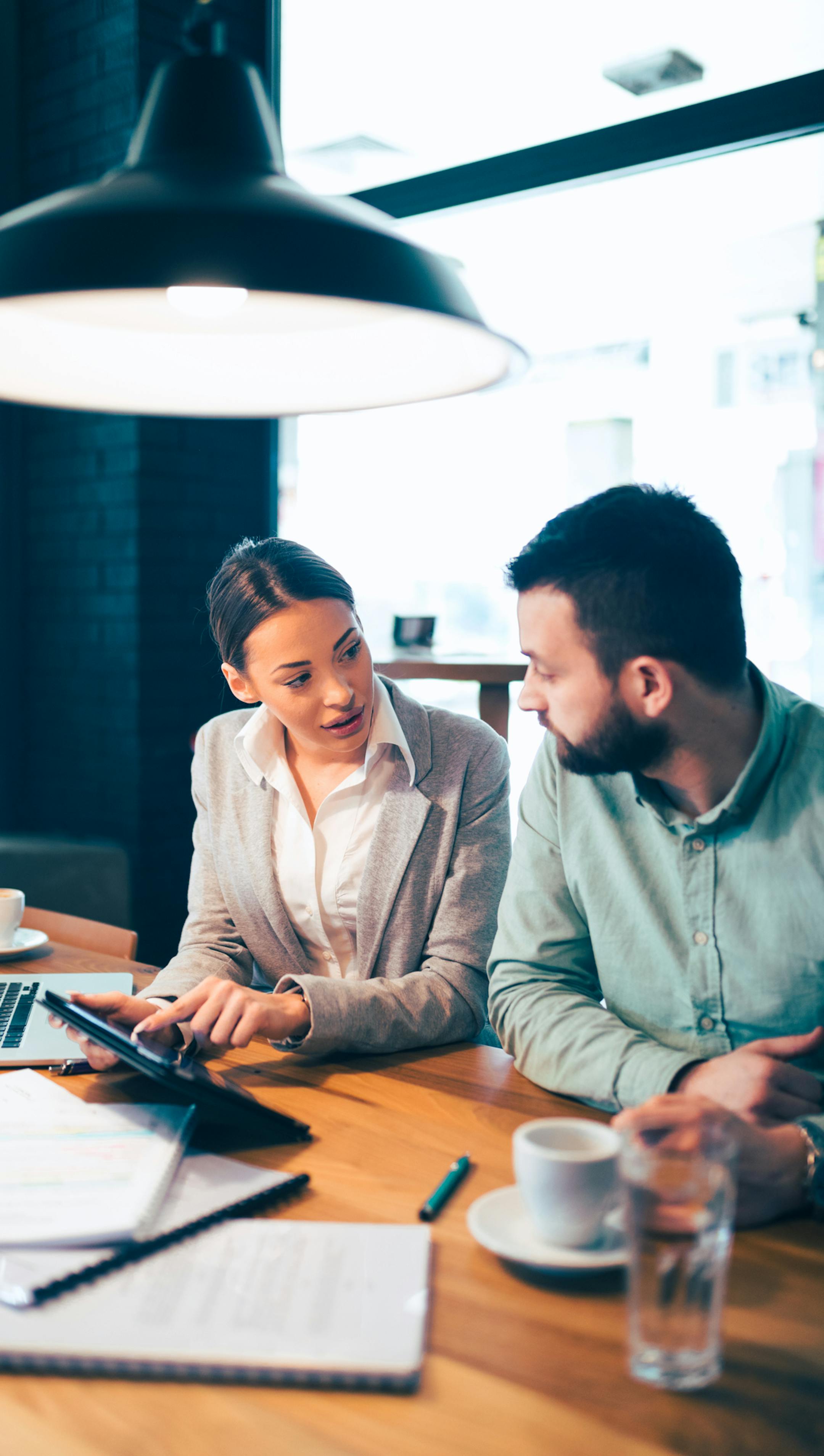 Two creative business partners discussing new business ideas using digital tablet in the office.