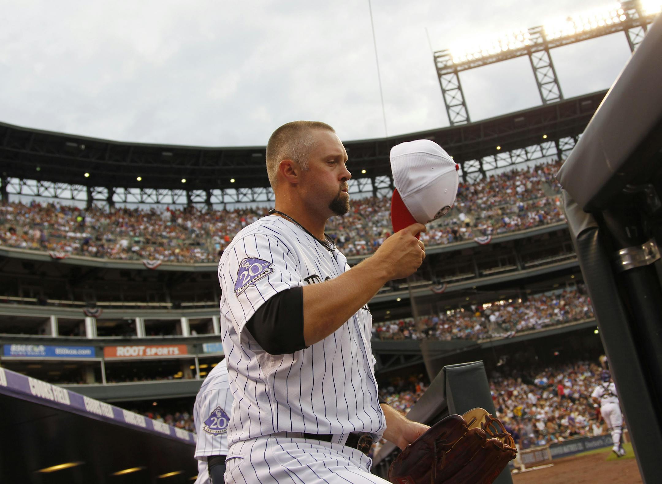 Colorado Rockies right fielder Michael Cuddyer dons his cap and heads to his position to face the Los Angeles Dodgers in the first inning of the Rockies' 9-5 victory in a baseball game in Denver on Thursday, July 4, 2013. (AP Photo/David Zalubowski)