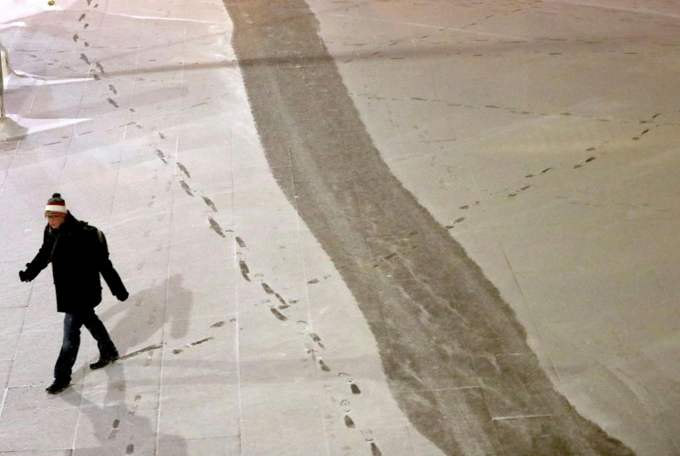 A pedestrian makes fresh tracks in the new snow outside the US Bank Plaza Wednesday, Jan. 11, 2016, in Minneapolis, MN.