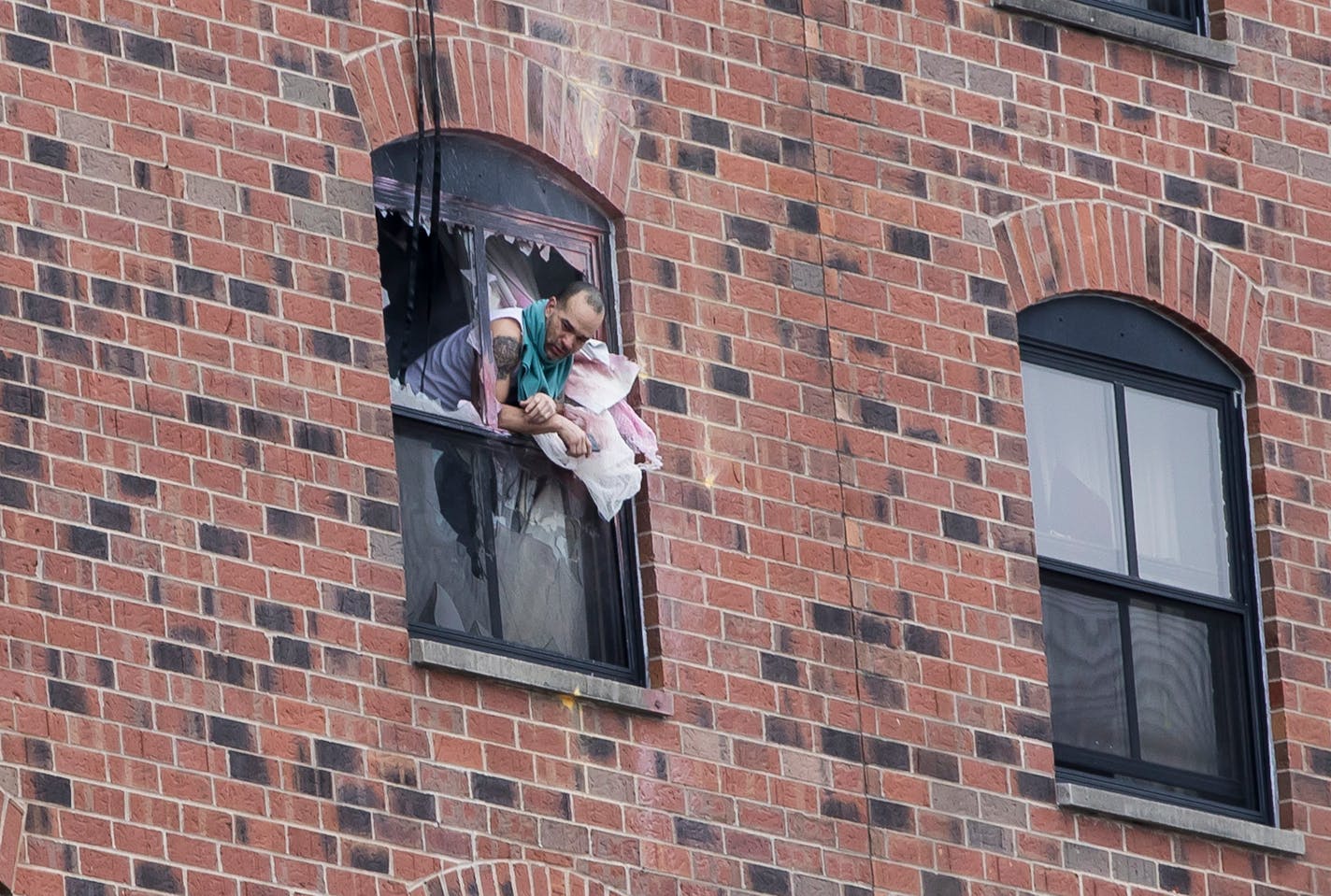 A man leaned out a window where a suspect has been on a stand off with police for over a day on Tuesday, January 30, 2018, at the Graduate Hotel at the University of Minnesota in Minneapolis.