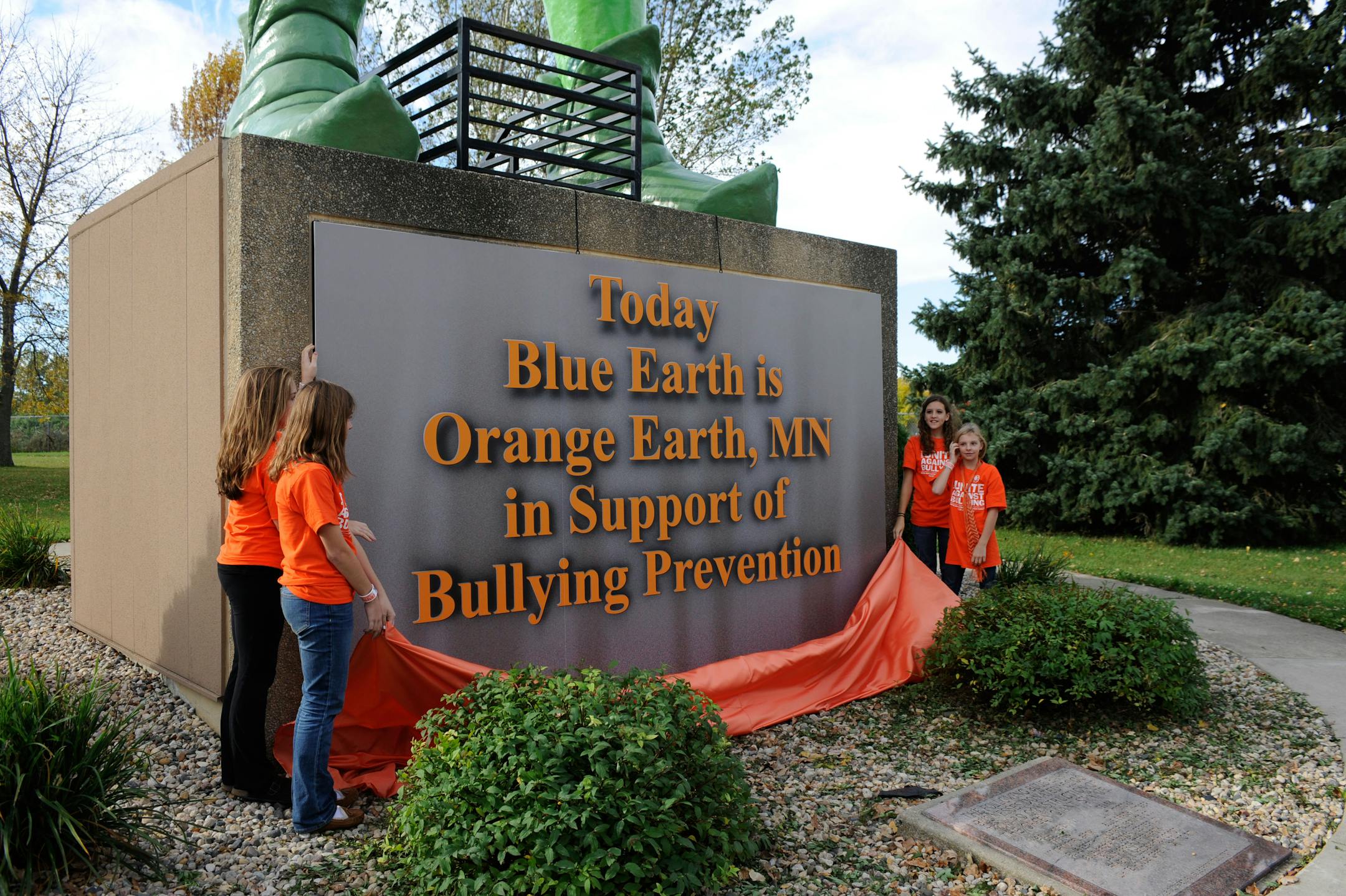 From left; Julia Hanson, 13, Lauren Schoenfelder, 14, Malarie Scholtes, 14 and Izzy Barnett,11, took their turn to unveil the new Blue Earth welcome sign Wednesday, Oct. 9, 2013 in Blue Earth, Minnesota. Blue Earth changed its name to Orange Earth, along with the 55 foot Green Giant's toga. Orange is the designated color for National Bullying Prevention Month. (Craig Lassig /AP Images Green Giant)