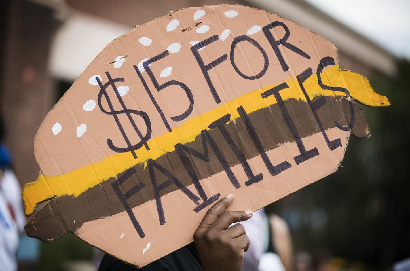 A man holds a sign shaped like a cheeseburger during a rally and march supporting $15 minimum wage on W. Broadway Avenue. ] (Leila Navidi/Star Tribune) leila.navidi@startribune.com BACKGROUND INFORMATION: Activists supporting a $15 minimum wage rally and march outside corporate fast food restaurants, payday lenders and a bank on W. Broadway Avenue in north Minneapolis on Monday, September 12, 2016. The activists are pushing for an ordinance passage at City Hall this year for a $15 minimum wage i