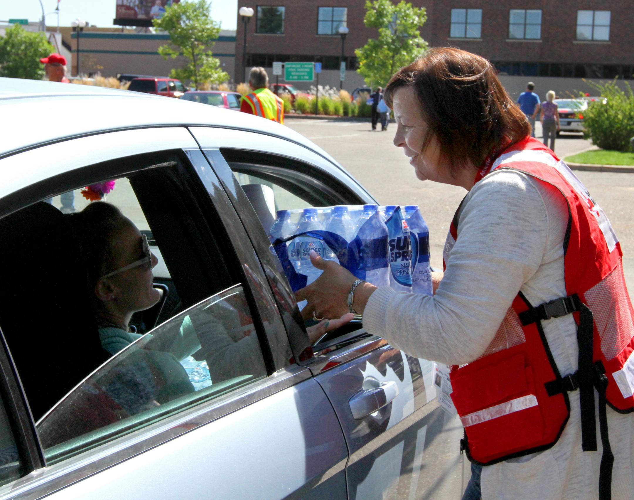 Red Cross volunteer Tina Jay hands bottled water to Brainerd residents Saturday at the Brainerd City Hall parking lot. Super America donated 1800 cases of water and it was handed out by volunteers from the fire department, Salvation Army and Red Cross volunteers. (Kelly Humphrey, Brainerd Dispatch)