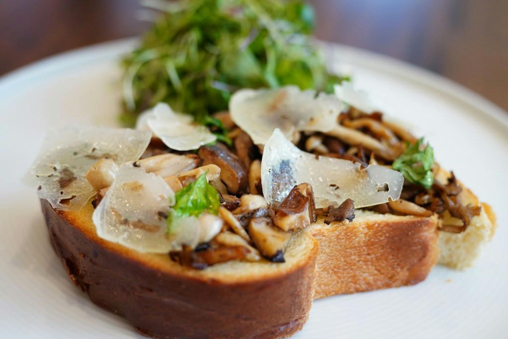 The roasted mushroom toast has a toasted brioche, white wine sauce, and manchego cheese.