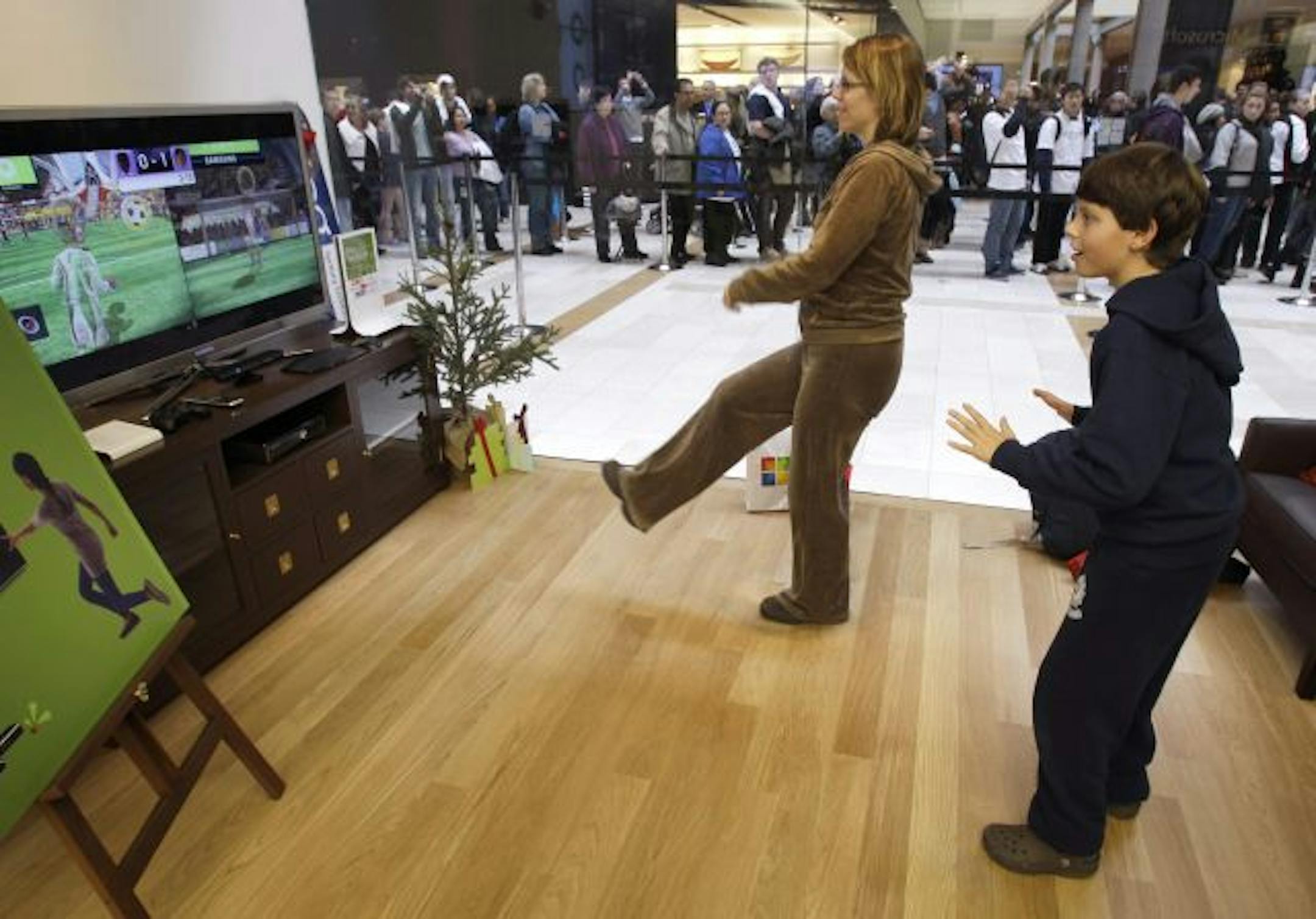 Aidan Bullard, 9, right, plays soccer on an Xbox 360 Kinect with his mother, Molly Bullard, second from right, at the grand opening of a Microsoft Store, Thursday, Nov. 18, 2010, in Bellevue, Wash. The store is the seventh Microsoft Store to open in the U.S., but the event garnered extra attention due to Microsoft's nearby headquarters in Redmond, Wash.