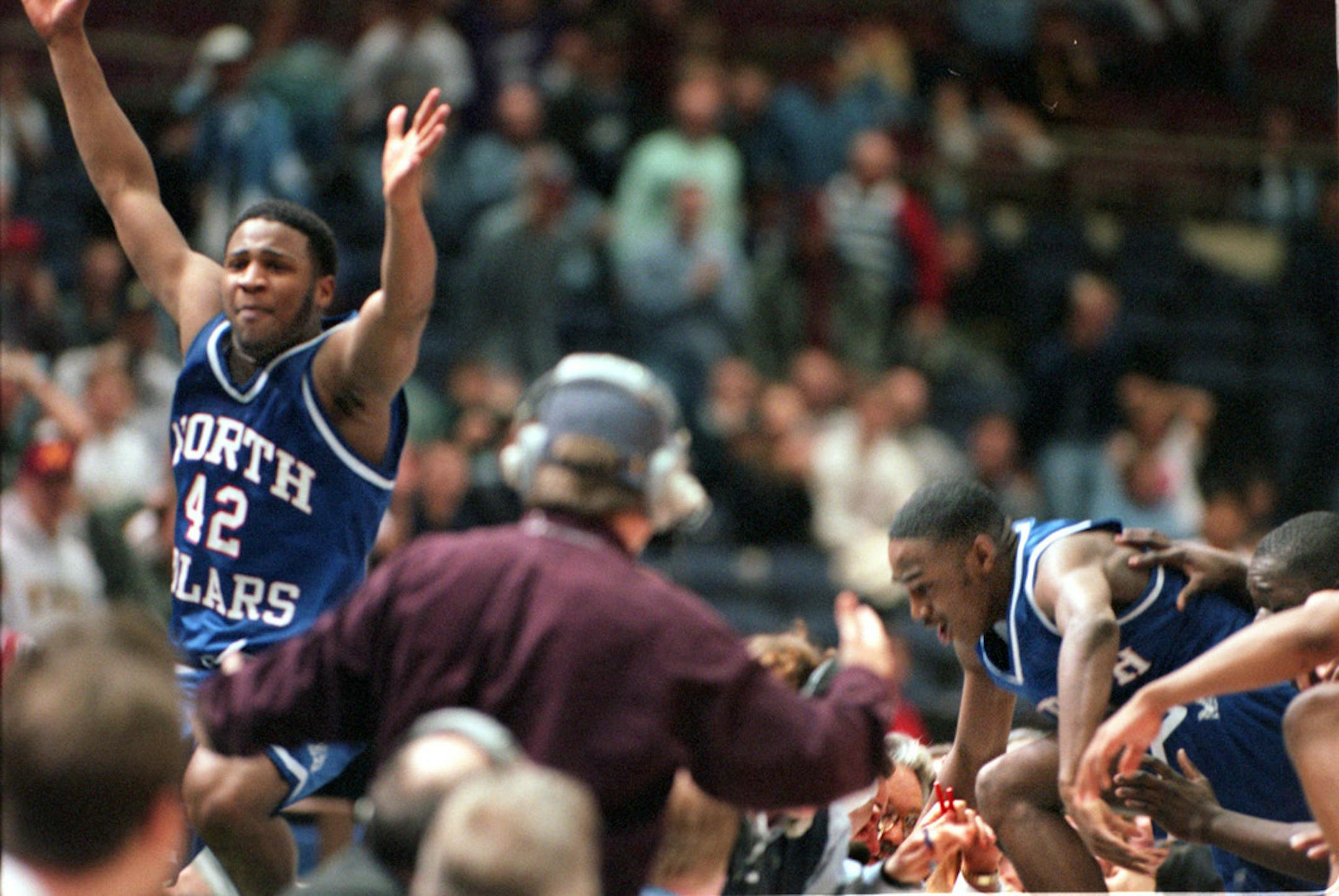 NORTH'S KHALID EL-AMIN left JUMPS OVER THE SCORER'S TABLE IN JUBILATION AFTER SCORING THE WINNING BASKET TO BEAT SAINT THOMAS ACADEMY AT THE CIVIC CENTER.