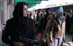 A Pakistani female police commando stands guard, as Indian Sikh pilgrims arrive at Wagah railway station near Lahore, Pakistan, Friday, Nov. 20, 2015.
