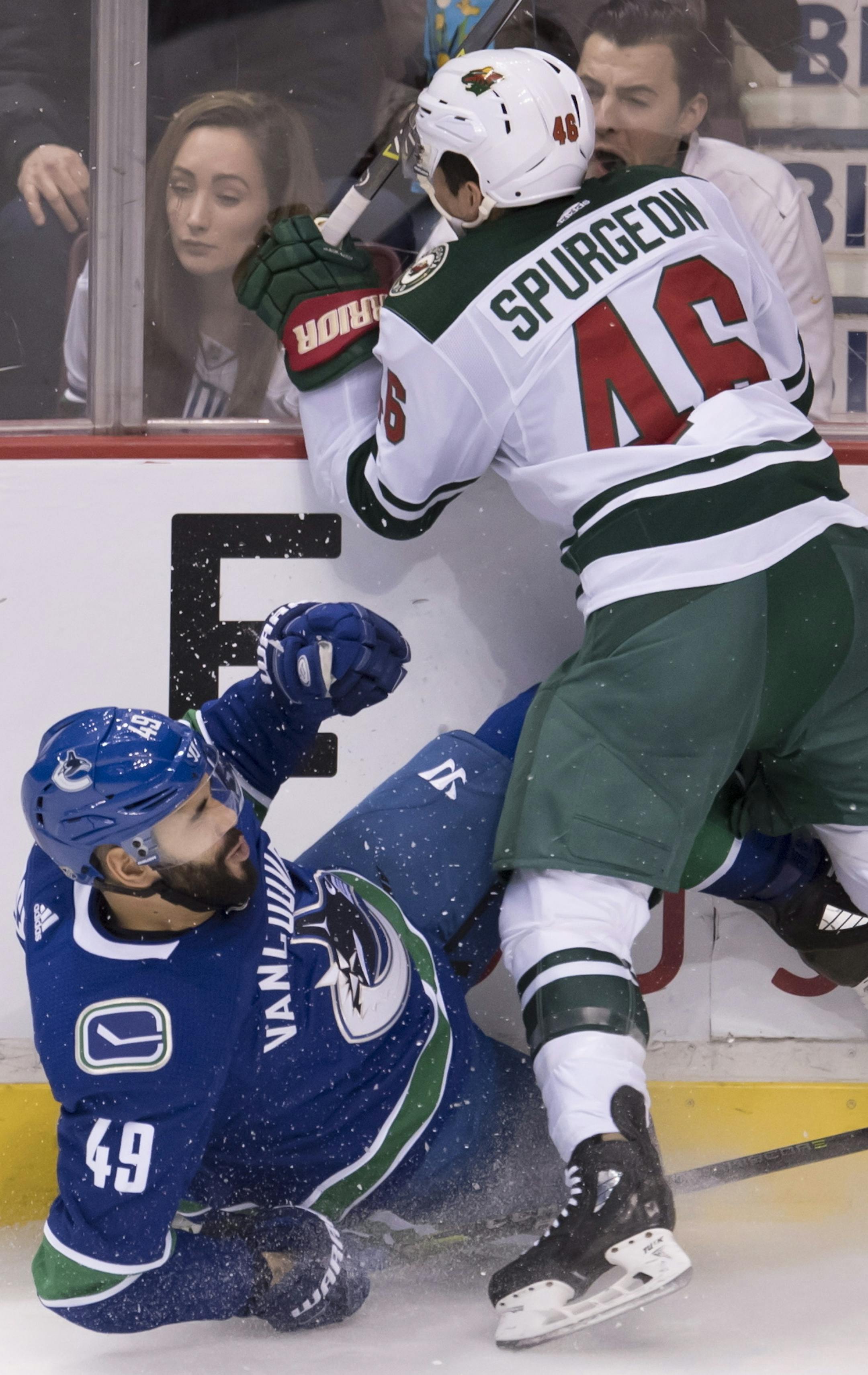 Minnesota Wild defenseman Jared Spurgeon (46) goes into the boards with Vancouver Canucks right wing Darren Archibald (49) during the second period of an NHL hockey game Friday, March 9, 2018, in Vancouver, British Columbia. (Jonathan Hayward/The Canadian Press via AP)