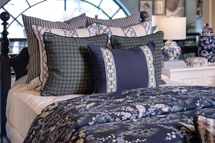 Bed with blue and white linens in different patterns.