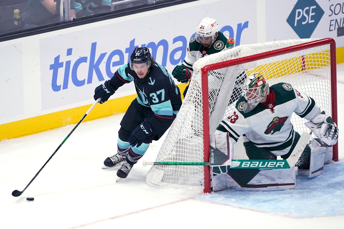 Seattle Kraken center Yanni Gourde skates behind Wild goaltender Cam Talbot during the second period