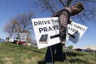 George DeCola, of Richmond, Va., places Drive Thru Prayer signs at a shopping center Thursday April 2, 2020, in Richmond, Va. DeCola, who is a worship