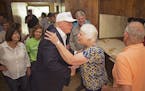 Republican presidential candidate Donald Trump, center, comforts flood victim Olive Gordan with her husband Jimmy, right, during tour of their flood d