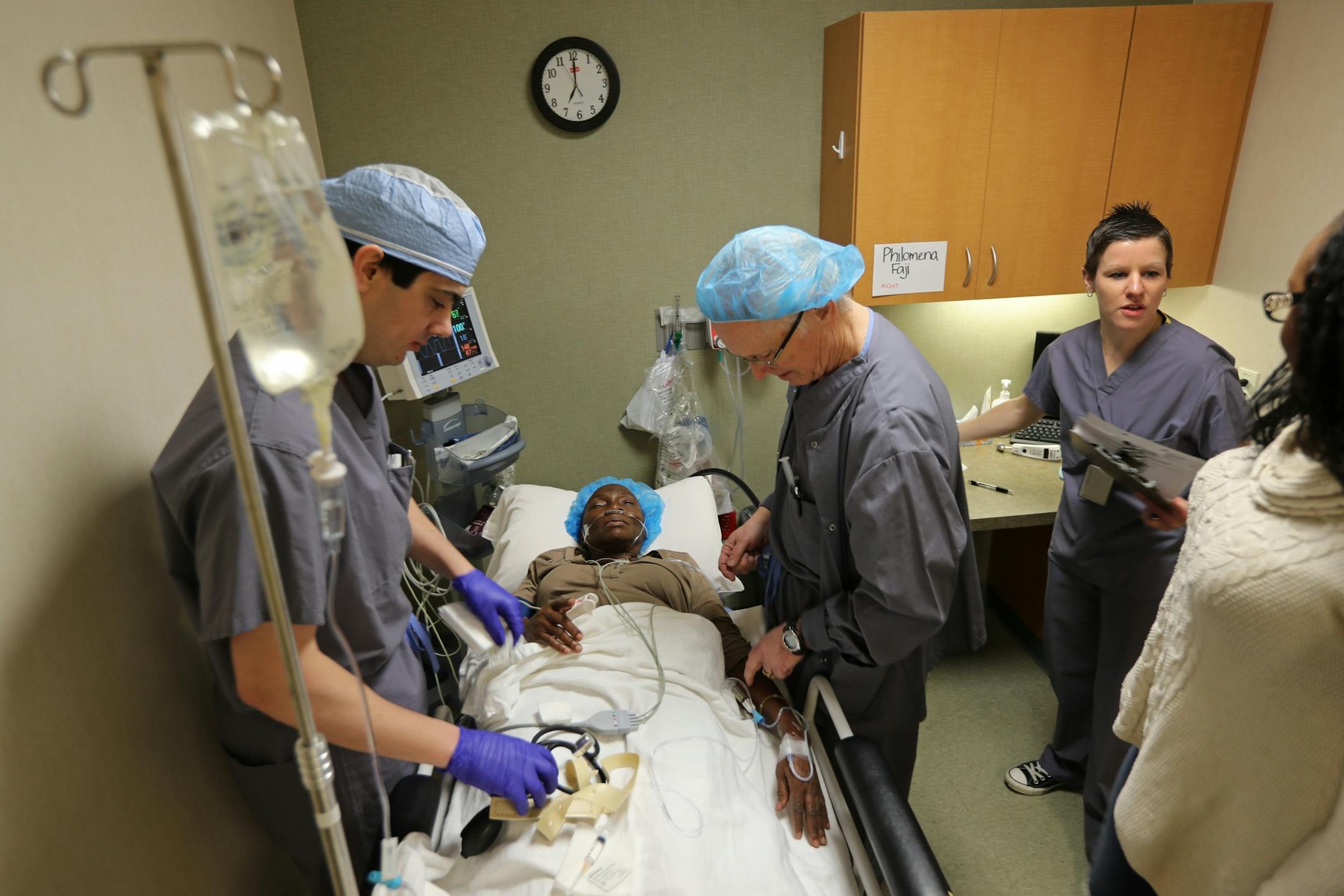Dr. Walter Parker (left) and Gary Hagen prepare Philomena Faji for cataract surgery while Sarah Payton speaks to Philomena's daughter Victoria Afolavan (right).