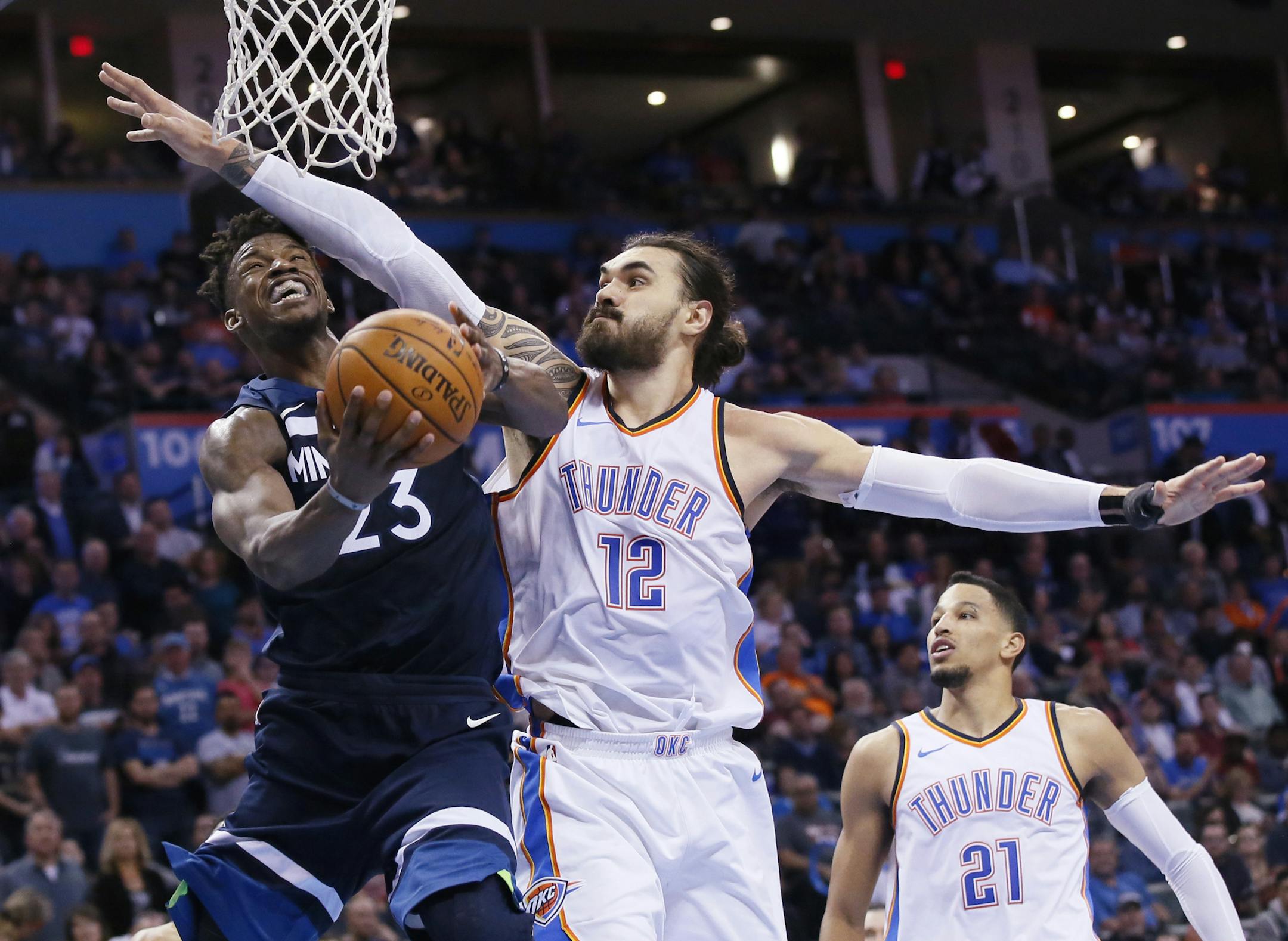 Minnesota Timberwolves guard Jimmy Butler (23) is fouled by Oklahoma City Thunder center Steven Adams (12) as he shoots during the fourth quarter of an NBA basketball game in Oklahoma City, Friday, Dec. 1, 2017. Oklahoma City won 111-107. (AP Photo/Sue Ogrocki)