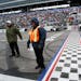 Track security guards Patrick Reyes, left, and Richard Gyure stood by the start-finish line as blowers worked on the track during Sunday's rain delay 