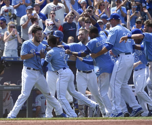 Royals players swarmed Eric Hosmer (35) after the first baseman's walk-off double beat the Twins on Sunday. The defending AL champion Royals continue 