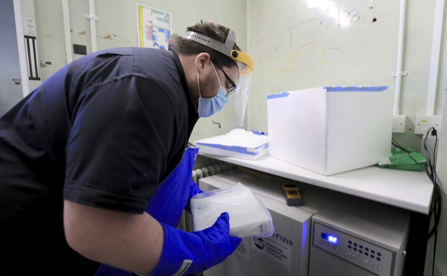 A pharmacy technician from Croydon Health Services prepares to store the first delivery of COVID-19 vaccine, at Croydon University Hospital in Croydon, England, Saturday Dec. 5, 2020. The first batch of Pfizer COVID-19 vaccine is delivered to the area in preparation for a public inoculation program, with each person needing two injections and the vaccine stored at extremely low temperature.