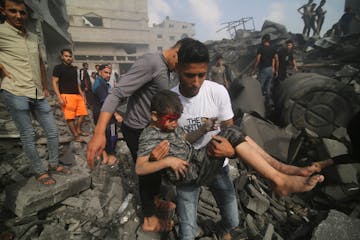 A Palestinian carries a child pulled out of a building hit in the Israeli bombardment of the Gaza Strip in Rafah, Sunday, Oct. 22, 2023. (AP Photo/Hat