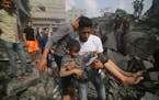 A Palestinian carries a child pulled out of a building hit in the Israeli bombardment of the Gaza Strip in Rafah, Sunday, Oct. 22, 2023. (AP Photo/Hat