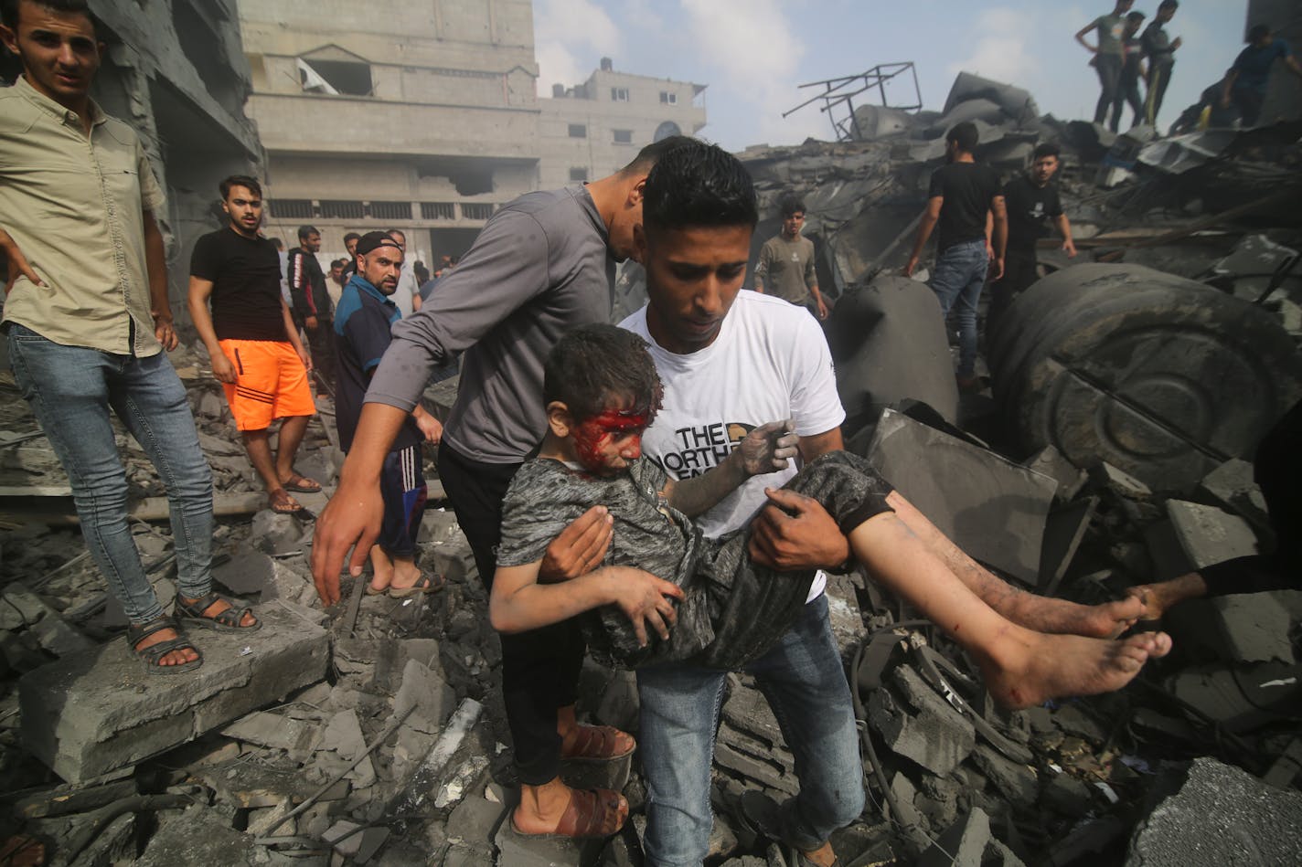 A Palestinian carries a child pulled out of a building hit in the Israeli bombardment of the Gaza Strip in Rafah, Sunday, Oct. 22, 2023. (AP Photo/Hatem Ali)